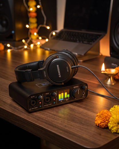 MOTU M2 audio interface with Samson SR350 headphones on a home studio desk with festive lights